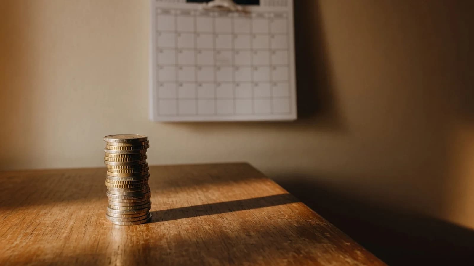 Monedas de euro junto a un calendario de pared